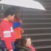 дети держат зонт над женщиной